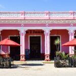 a pink building with red umbrellas in front of it